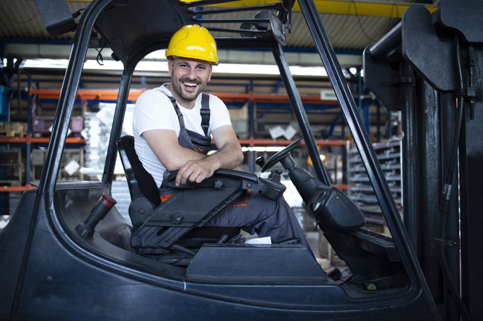 Portrait of professional forklift driver in factory's warehouse.